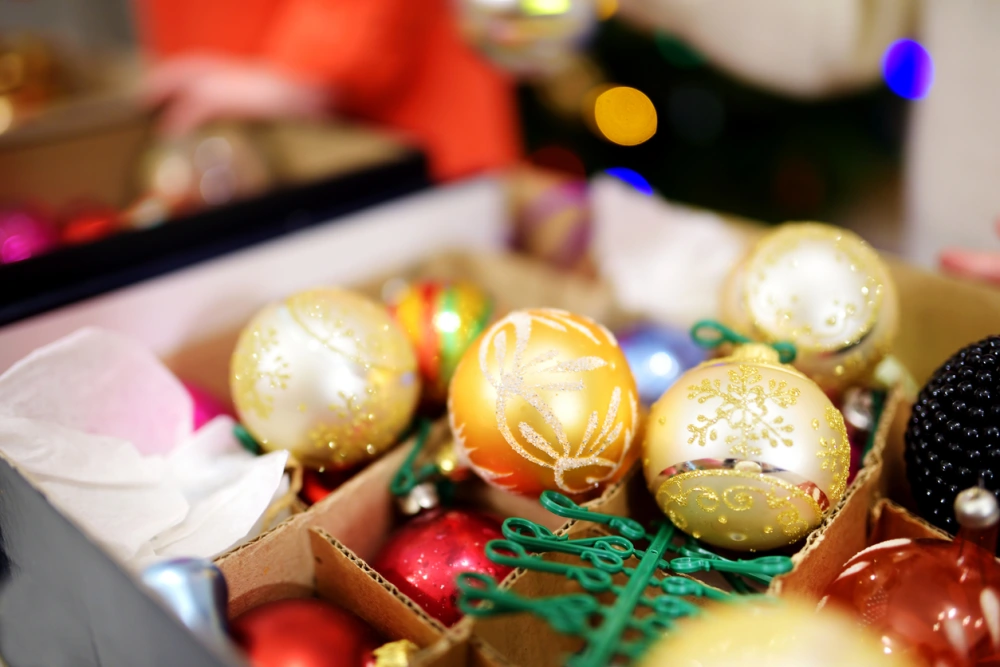 Gold, glittery Christmas tree ornaments sit on top of a box full of decorations