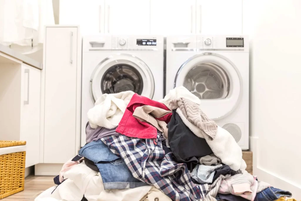 pile of laundry in front of washer and dryer