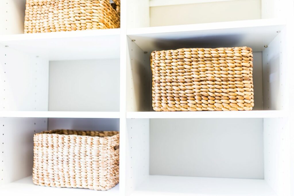 Three wicker baskets being stored in cubbies.