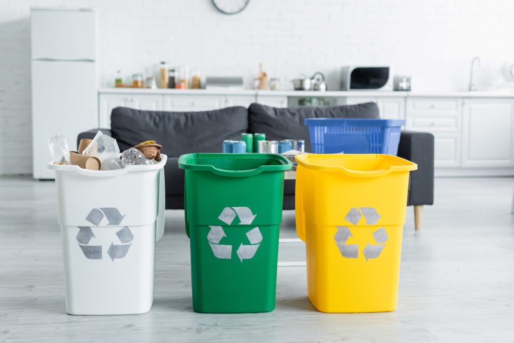 Three colored bins that symbolize organization and decluttering with a kitchen in the background. 