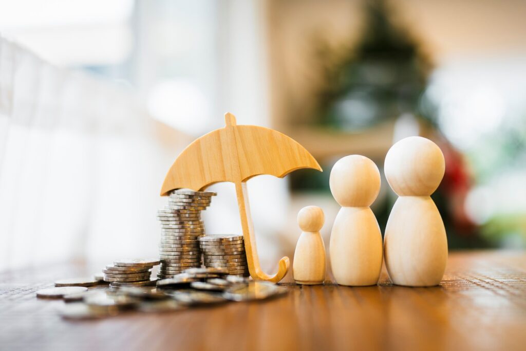Family dolls and an umbrella icon covering several coins to resemble the benefits of insurance.