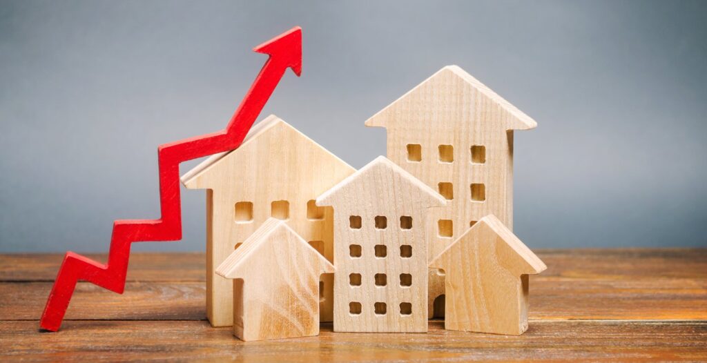 Miniature wooden houses next to a rising red arrow to resemble urban population growth.