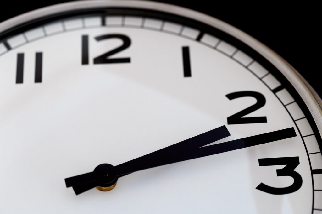 An analog clock reads around 2:13 and continues to tell time.